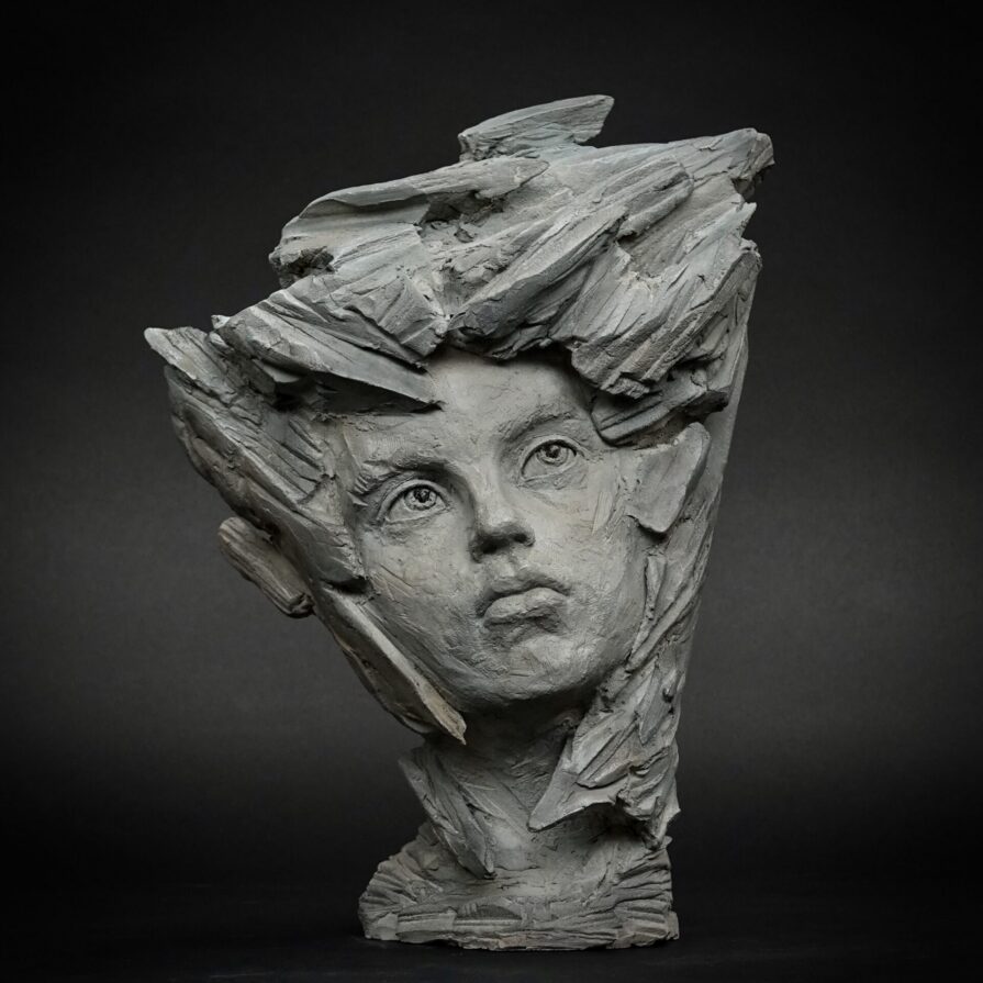 Sculpture de Sarah Scouarnec, portrait d'enfant en métamorphose pierre, patine grise